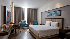 A bedroom at Geeta Sarovar Portico, Panipat featuring a double size bed, a flat TV screen on the wall, a chair, and a seating area.