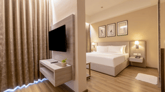 Executive Room with a wall-mounted TV console separating the living space from the bedroom at Golden Tulip - Sector 80, Gurugram.