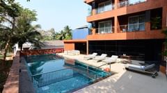 The outdoor swimming pool area with lounging chairs placed besides it at Golden Tulip Vagator, Goa