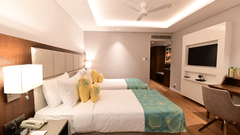 A room at Golden Tulip Vagator, Goa with twin beds, a television and a work desk and chair set up