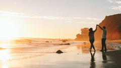 A couple dancing on the beach with a sunset in the background 