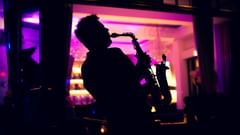 Silhouette of a musician performing indoors, set against vibrant lighting .