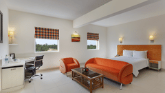 Room at Hometel Roorkee featuring a bed, a sofa set with centre table, and a workstation.