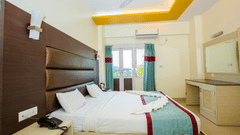 Interiors of Sea View Room, one of finest Port Blair Stay at Hotel Shompen, featuring a large bed, upholstered headboard, dressing table, and a large window offering outdoor views.