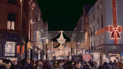 a decorated street with lights everywhere and people walking below enjoying the views