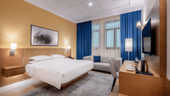 a king bed with a painting hung above inside the Classic King Bed - La Maison Hotel, Doha