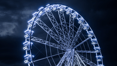 A view from below of a ferris wheel with lights on during the night - Theme Parks in Doha