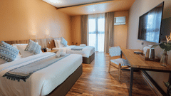 Modern hotel room at Lamari Siargao with twin beds, woven headboards, wooden floors, and natural decor overlooking tropical gardens.