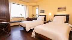 A side view of the executive bed with  comfy twin beds and a window with a view at Marasa Sarovar Portico, Rajkot