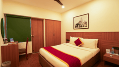 Bedroom in warm lighting featuring a double bed and a framed painting over it and a nightstand next to it