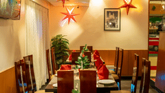 Restaurant decorated for Christmas featuring dining seating arrangements with chairs and tables with cutlery placed