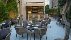 An outdoor dining area at Nemesia includes tables and chairs arranged along a walkway.