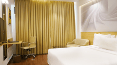 An image of a bedroom featuring a double size bed, flat TV screen, work and desk,  and other items - Nemsia