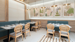 A restaurant interior with a long dining table and a plant wall.