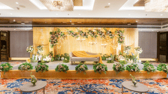 An event stage setup at Nirvana Sarovar Portico, Gorakhpur featuring a lounge couch, floral arrangements, and patterned carpet.