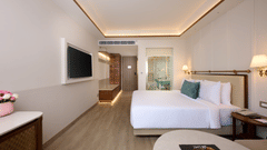Standard Room at Prachi Sarovar Premiere, Bhubaneswar, with a bed, a wall-mounted television, a round table, and an entrance corridor.