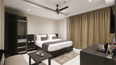 Premium Room at Pride Biznotel Canopus, Digha featuring a plush bed in front of a TV mounted on the wall and a sitting space with a couch and a coffee table