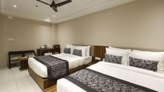 Superior Twin Room at Pride Biznotel Canopus, Digha featuring two double beds placed next to each other and a sitting space in the background featuring a two-seater sofa and a coffee table next to the work desk