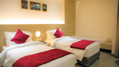 Deluxe Twin Bedroom at Pride Biznotel Haldwani featuring a couple of twin beds with a common headboard with warm lighting