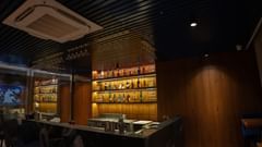 Image of a bar with wooden decor and drinks stacked in the shelf at Pride Elite Daman.