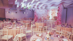 An elegant event space decorated predominantly in pink hues, with tables set for a celebration.