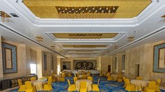 Banquet hall with seats and tables draped in yellow clothes at Pride Hotel Bhopal