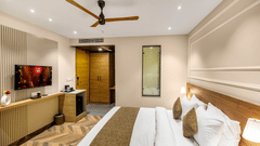 Superior Room at Pride Hotel Rishikesh featuring a plush bed in front of a TV mounted on the wall with coffee maker on the side table below it