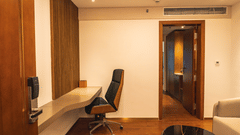 A sleek study desk, an ergonomic office chair, and a wooden doorway at Pride Plaza Indore.
