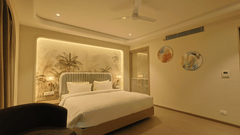 Pride Premier Alwar | A room with a large bed, spreads, pillows, and a cushion.