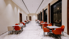 Pride Premier Alwar | A dining space with chairs and tables in a pathway.
