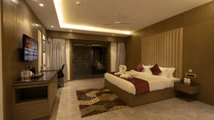 A modern hotel room with a large bed, desk, and TV at Pride Resort, Jodhpur, featuring warm ambient lighting.