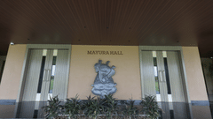 The entrance of Mertura Hall at Pride Resort, Jodhpur, featuring a decorative emblem and flanked by glass doors.