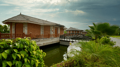 A scenic shot of the hotel cottages surrounded by greenery under dramatic skies - Royal Tulip, Chitwan