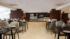 The dining area at Royal Tulip, Kathmandu, with tables set and the pastry counter visible in the background.