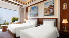Hotel room at Royal Tulip Shivapuri National Park - Kathmandu with twin beds, clean linens, framed artwork, and a large window facing the hills.