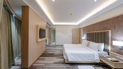 A suite in Ajmer featuring a king size bed, a wall-mounted television, and a night stand - Sarovar Portico, Ajmer