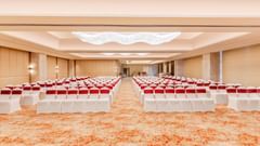 A banquet hall at Sarovar Premiere Alwar with rows of chairs and a patterned carpet on the floor.