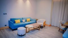 A seating area featuring a cosy couch, a coffee table, a upholstered chair and stool - Serene Sarovar Premiere Hargeisa