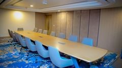 A meeting room with carpeted floors, a long table, and ergonomic chairs - Serene Sarovar Premiere Hargeisa