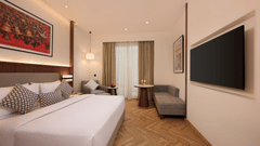 Skywings Sarovar Portico Mathura premium room with king bed, red framed wall art, herringbone wood flooring, pendant lights, and warm interiors.