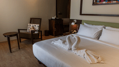 a double bed with dove towers, a chair and table inside Sky Villa - Symphony Samudra Beachside Jungle Resort And Spa, Port Blair