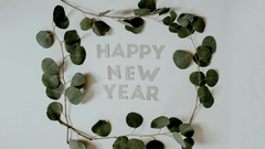 Happy new year written in capitalised letters with stands of leaves covering the wordings