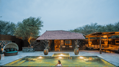 Swimming pool of The Blackbuck Lodge, Velavadar featuring a cottage and evening lighting.