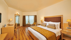 Image of a room at Pride Premier Nagpur featuring a plush bed with cushioned wooden headboard with wooden nightstands on both sides