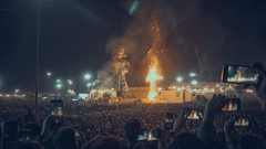A large crowd watching an effigy burn at night.