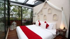 A bed beautifully set up in an open-air space, surrounded by an enchanting view with nature and sky above