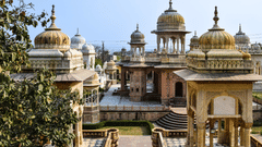 Multiple domed structures with arched openings and a walkway with clear blue sky in the background.