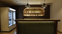 An image of bar counter displaying various liquor bottles placed on shelves and refrigerator at Tulip Inn, Zirakpur