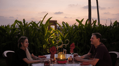 A couple enjoys a romantic outdoor dinner at sunset with lush greenery around them at Uday Samudra Leisure Beach Hotel 