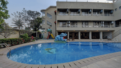 Hotel exterior view with large swimming pool at VITS Lonavala.